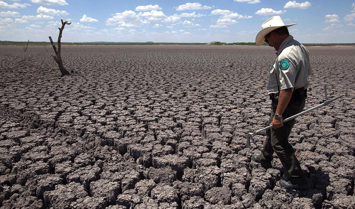 Police officer walks across cracked lakebed